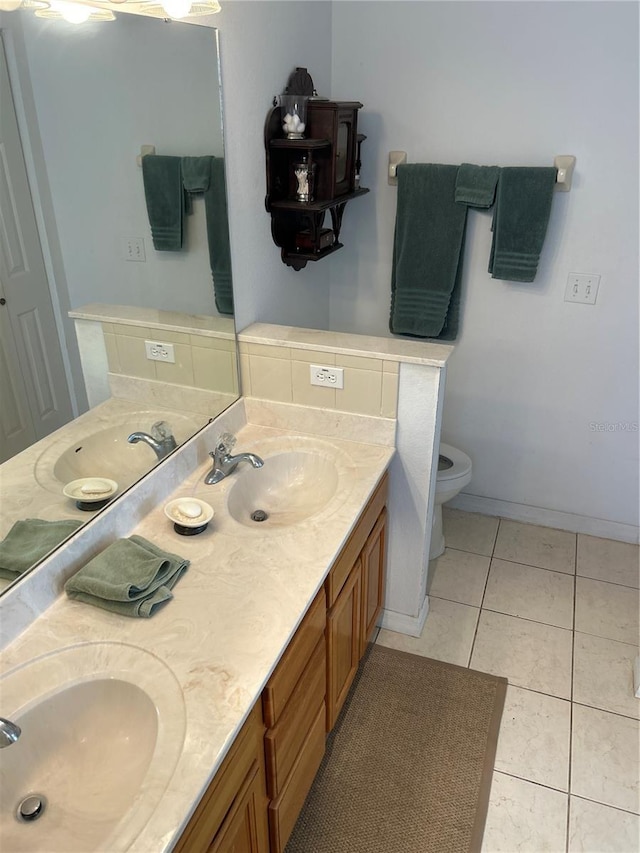 bathroom with toilet, vanity, and tile patterned floors