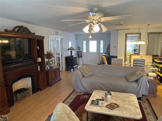 living room with ceiling fan, light wood-type flooring, and a textured ceiling