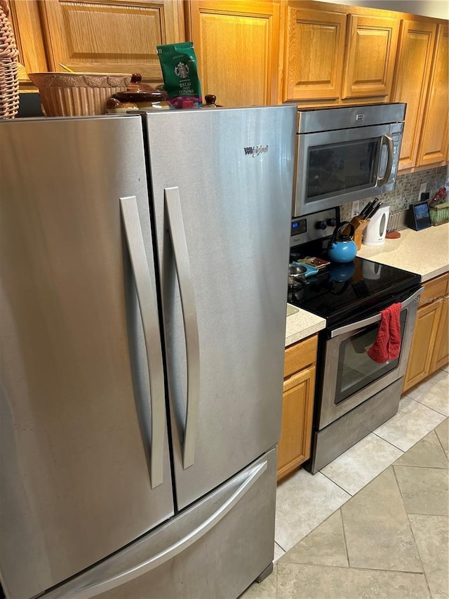 kitchen featuring light tile patterned floors, backsplash, and appliances with stainless steel finishes