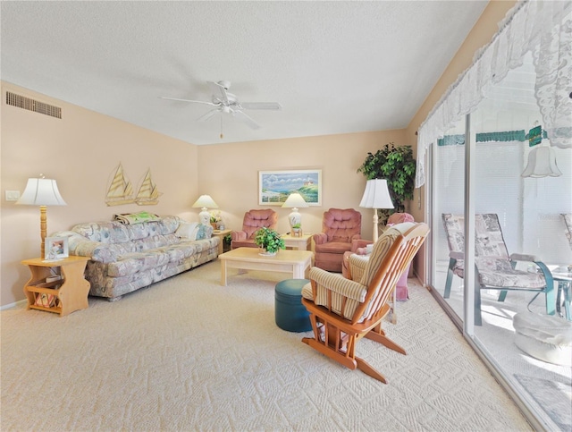 living room with ceiling fan, carpet floors, and a textured ceiling