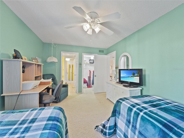 carpeted bedroom featuring connected bathroom, ceiling fan, a textured ceiling, a walk in closet, and a closet