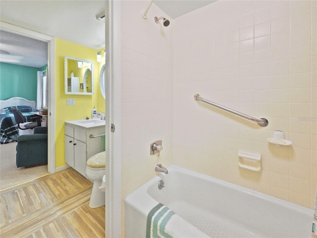 full bathroom with vanity, hardwood / wood-style floors, tiled shower / bath combo, and toilet