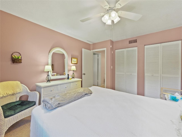 carpeted bedroom featuring ceiling fan and two closets