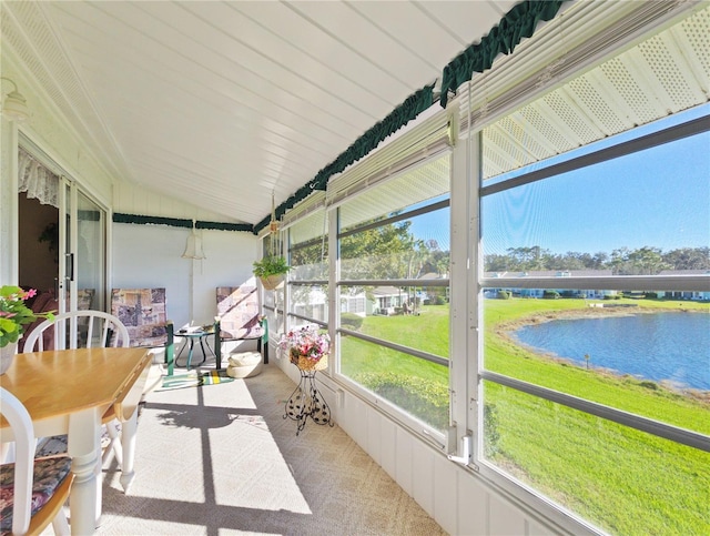 sunroom / solarium with a water view and vaulted ceiling