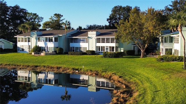 back of house with a lawn and a water view