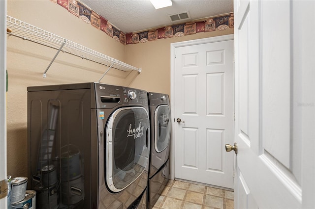 laundry area featuring washing machine and dryer and a textured ceiling