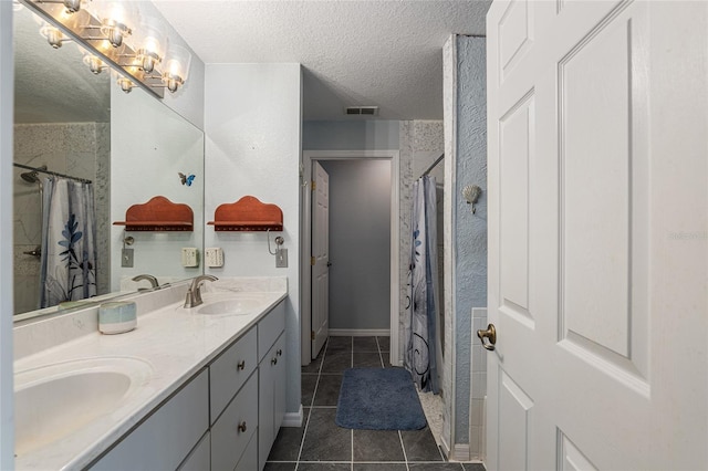 bathroom featuring a textured ceiling, walk in shower, vanity, and tile patterned floors