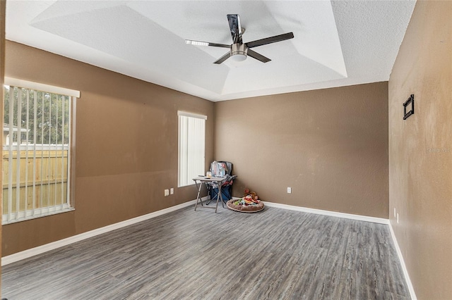 interior space featuring dark hardwood / wood-style flooring, a textured ceiling, ceiling fan, and a tray ceiling