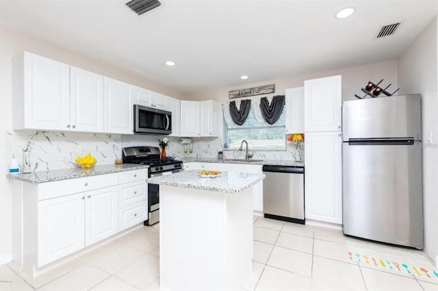 kitchen featuring backsplash, stainless steel appliances, sink, a center island, and white cabinetry