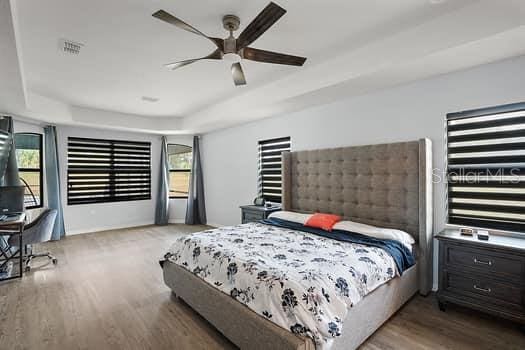 bedroom featuring a raised ceiling, ceiling fan, and hardwood / wood-style flooring