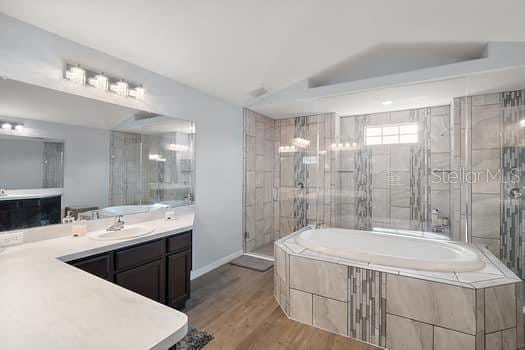 bathroom with separate shower and tub, vanity, vaulted ceiling, and hardwood / wood-style flooring