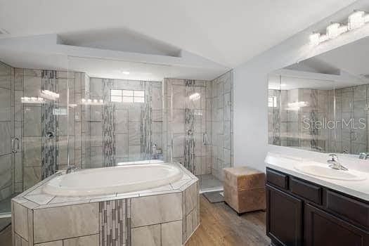 bathroom with vanity, plus walk in shower, wood-type flooring, and vaulted ceiling