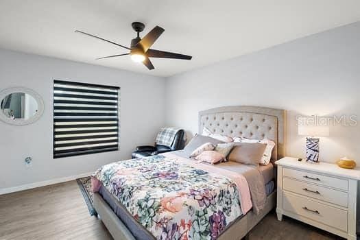 bedroom with dark hardwood / wood-style flooring and ceiling fan