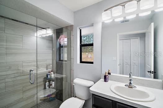 bathroom featuring vanity, an enclosed shower, and toilet