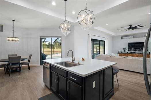 kitchen with ceiling fan, sink, stainless steel dishwasher, pendant lighting, and a center island with sink