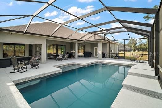 view of swimming pool with glass enclosure and a patio area