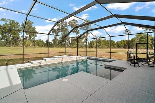 view of swimming pool featuring a lawn, glass enclosure, and a patio area