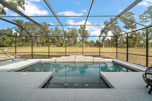 view of swimming pool with a patio, a lanai, and a lawn