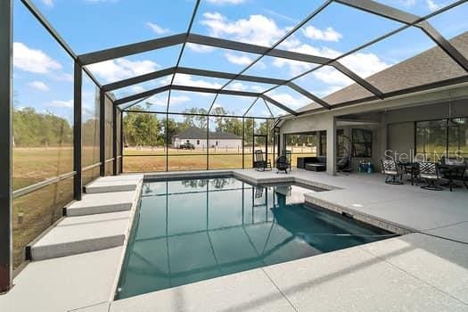 view of swimming pool featuring a lanai and a patio