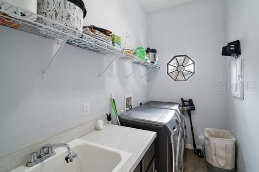 laundry area featuring hardwood / wood-style flooring, washer and clothes dryer, and sink