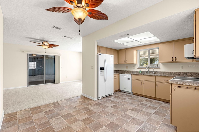 kitchen featuring a textured ceiling, white appliances, light colored carpet, sink, and cream cabinetry