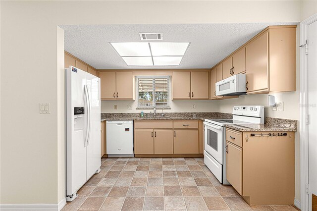 kitchen with a textured ceiling, white appliances, light brown cabinets, and sink