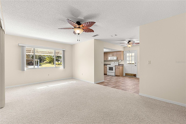 unfurnished living room with ceiling fan, a healthy amount of sunlight, light colored carpet, and a textured ceiling