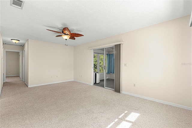 spare room featuring ceiling fan, light colored carpet, and a textured ceiling