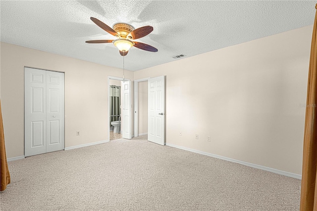 unfurnished bedroom with ceiling fan, light carpet, and a textured ceiling