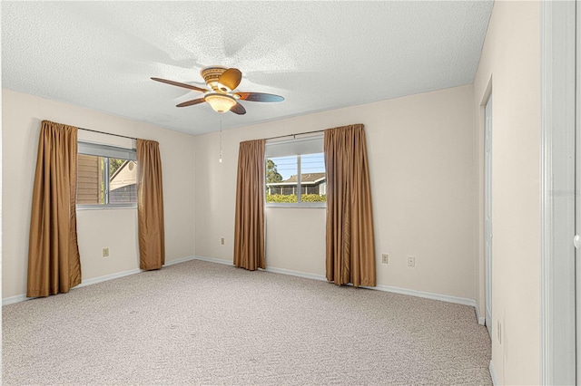 unfurnished room with a wealth of natural light, light carpet, and a textured ceiling