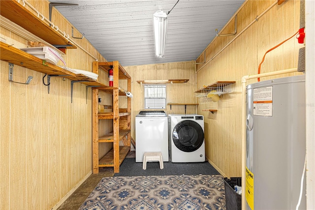 laundry room with washing machine and dryer, water heater, and wood walls