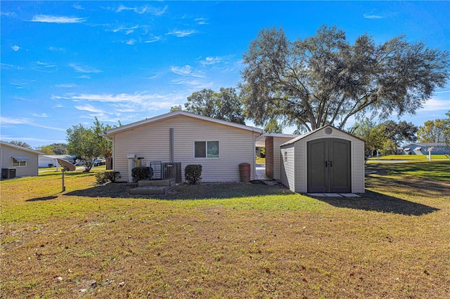 rear view of house with a lawn and a storage unit