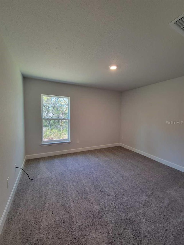 carpeted empty room with visible vents, baseboards, and a textured ceiling