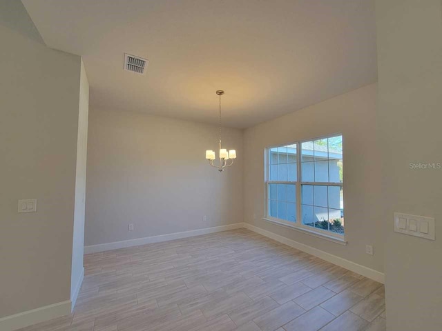 unfurnished room with a chandelier, visible vents, light wood-style flooring, and baseboards