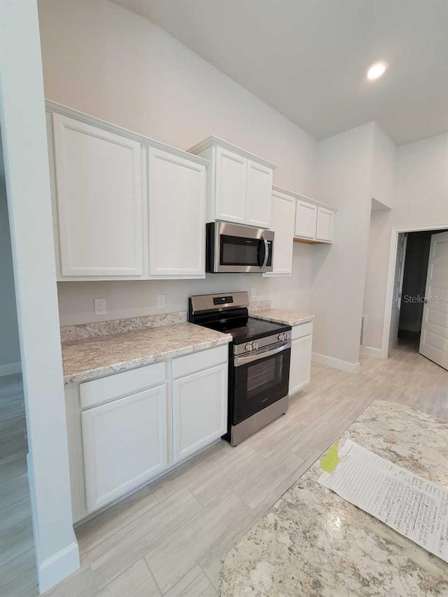 kitchen featuring white cabinetry, recessed lighting, stainless steel appliances, light wood-style floors, and baseboards