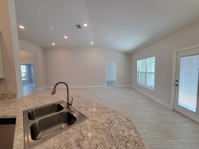 kitchen featuring light stone counters, recessed lighting, a sink, vaulted ceiling, and dishwasher