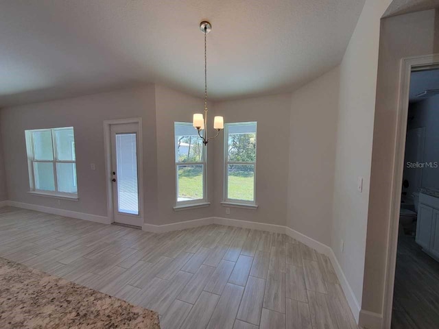 unfurnished dining area with baseboards, a notable chandelier, and light wood finished floors