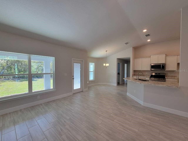 kitchen with visible vents, a sink, vaulted ceiling, white cabinets, and appliances with stainless steel finishes