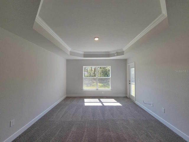 carpeted empty room featuring baseboards, a raised ceiling, and crown molding