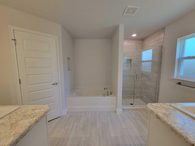 full bathroom featuring vanity, a shower stall, a bath, and visible vents