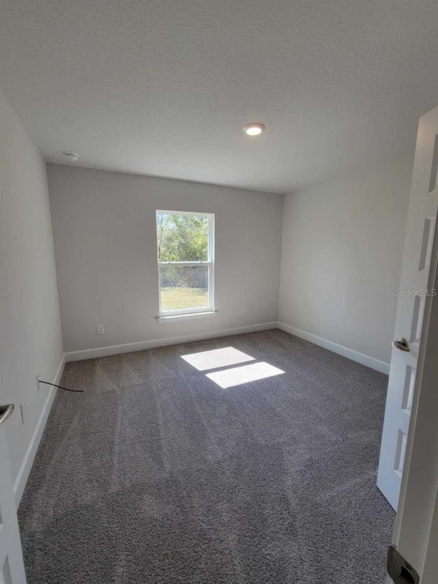 spare room featuring carpet flooring, a textured ceiling, and baseboards