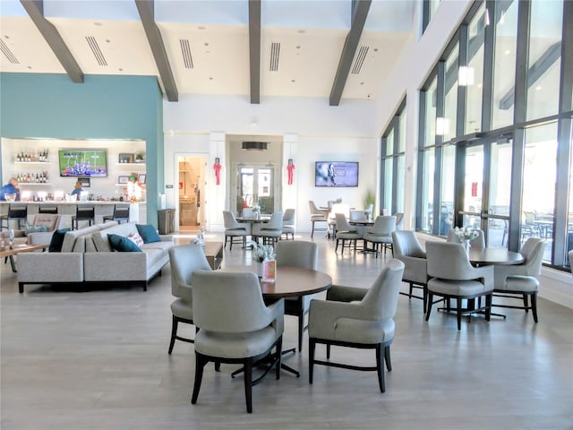 dining room with beam ceiling, visible vents, and a high ceiling