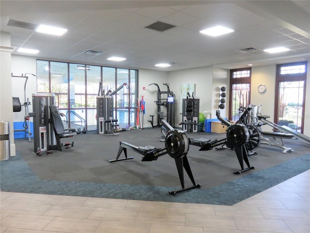 exercise room featuring expansive windows, a drop ceiling, and visible vents