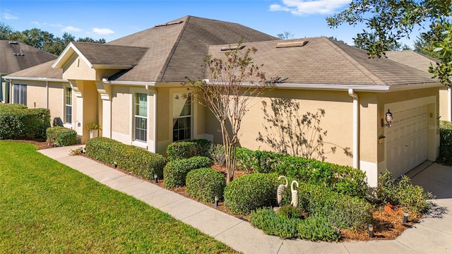 view of front of house with a shingled roof, a front yard, an attached garage, and stucco siding