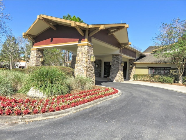 view of front of property featuring stone siding, driveway, and stucco siding