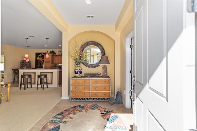 foyer entrance with light carpet, light tile patterned floors, visible vents, and baseboards