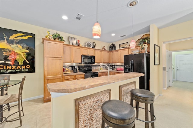 kitchen with a kitchen island with sink, visible vents, light countertops, black appliances, and pendant lighting