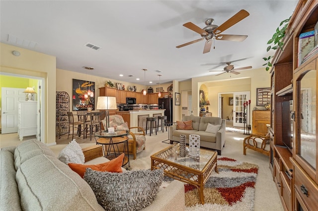 living area with visible vents and light carpet