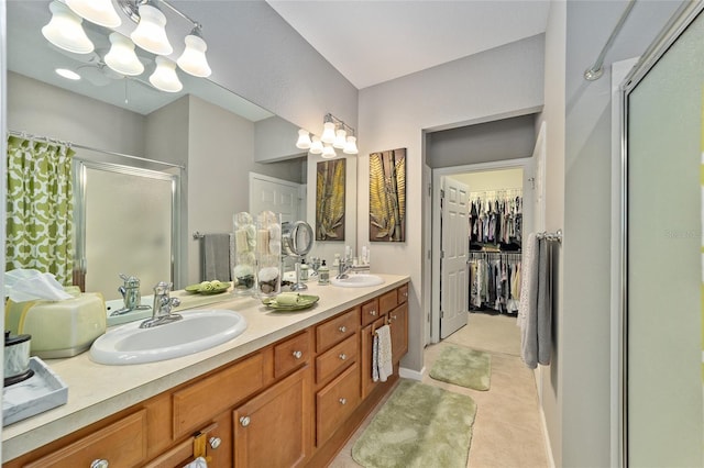 full bath featuring a spacious closet, double vanity, a sink, and a shower stall