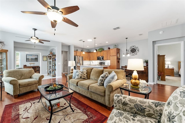 living room featuring dark hardwood / wood-style flooring, ceiling fan, and sink